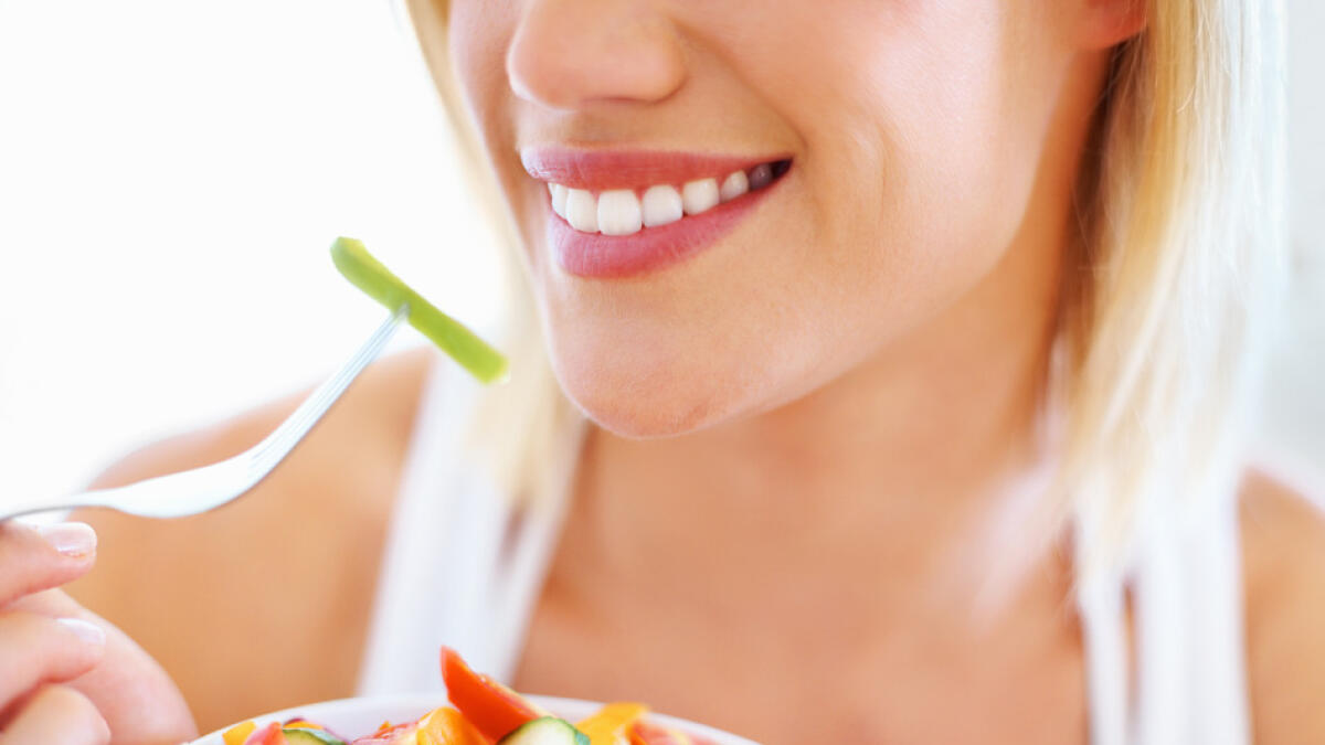 Cropped image of beautiful woman eating fresh vegetable salad