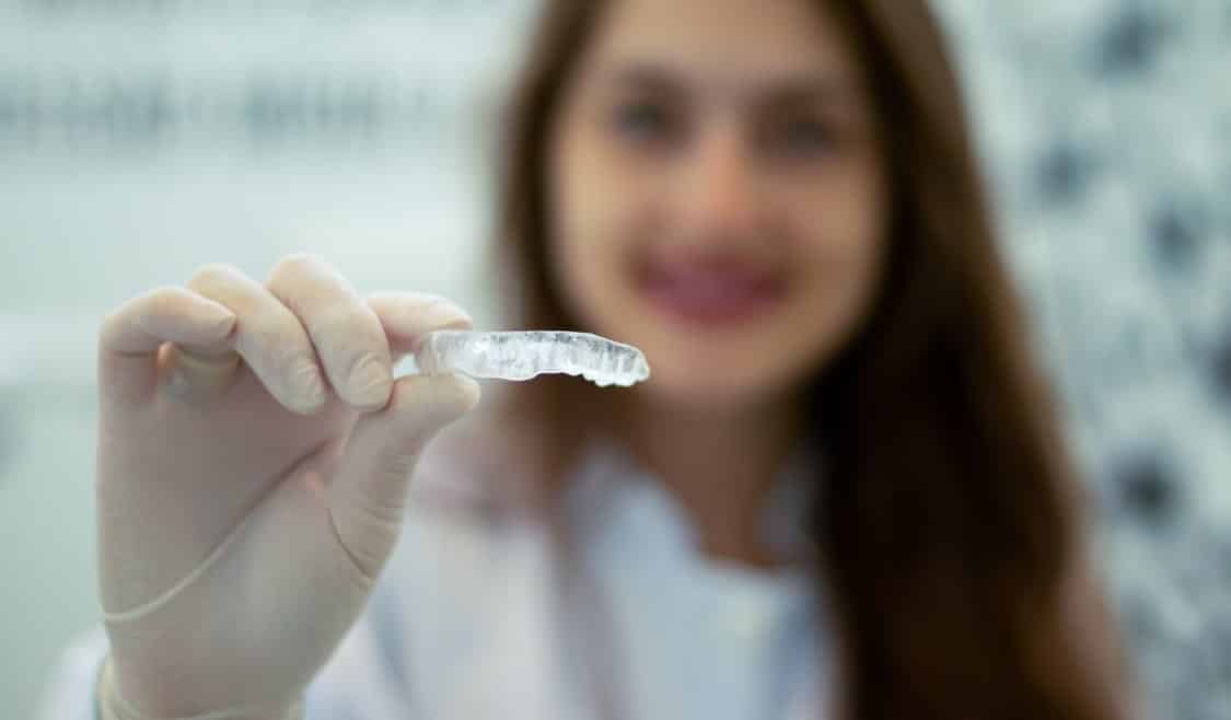 Dentist with invisalign in her hand and blurred 